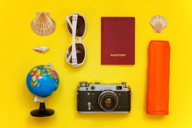Güneş kremi, çınar, bağbozumu kamera, pasaport, dünya, güneş gözlüğü ve kabuk sarı renkli şık modern moda arka plan üzerinde ile düz yatıyordu. Tatil seyahat yaz hafta sonu deniz macera seyahat kavramı