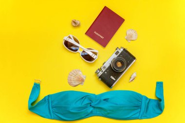 Düz Lay Bikini, çınar, bağbozumu kamera, küre, pasaport, güneş gözlüğü ve kabuk üzerinde sarı renkli şık modern moda arka plan ile. Tatil seyahat yaz hafta sonu deniz macera seyahat kavramı