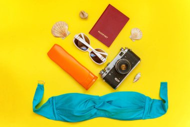 Düz Lay Bikini, çınar, bağbozumu kamera, pasaport, Güneş kremi, güneş gözlüğü ve kabuk üzerinde sarı renkli şık modern moda arka plan ile. Tatil seyahat yaz hafta sonu deniz macera seyahat kavramı