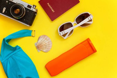 Düz Lay Bikini, çınar, bağbozumu kamera, pasaport, Güneş kremi, güneş gözlüğü ve kabuk üzerinde sarı renkli şık modern moda arka plan ile. Tatil seyahat yaz hafta sonu deniz macera seyahat kavramı