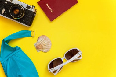 Düz Lay Bikini, çınar, bağbozumu kamera, pasaport, Güneş kremi, güneş gözlüğü ve kabuk üzerinde sarı renkli şık modern moda arka plan ile. Tatil seyahat yaz hafta sonu deniz macera seyahat kavramı