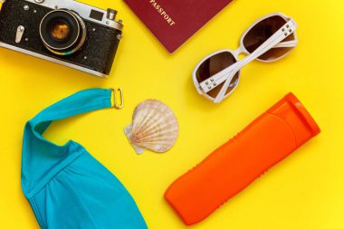 Düz Lay Bikini, çınar, bağbozumu kamera, pasaport, Güneş kremi, güneş gözlüğü ve kabuk üzerinde sarı renkli şık modern moda arka plan ile. Tatil seyahat yaz hafta sonu deniz macera seyahat kavramı