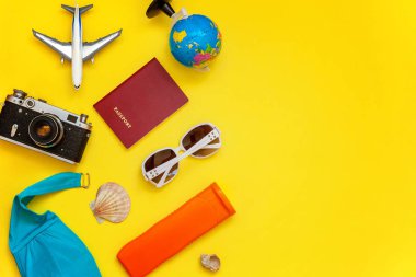 Düz Lay Bikini, çınar, bağbozumu kamera, dünya, Güneş kremi, pasaport, güneş gözlüğü ve kabuk üzerinde sarı renkli şık modern moda arka plan ile. Tatil seyahat yaz hafta sonu deniz macera seyahat kavramı