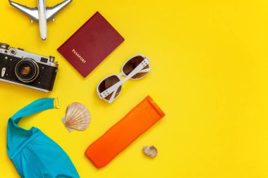 Düz Lay Bikini, çınar, bağbozumu kamera, pasaport, Güneş kremi, güneş gözlüğü ve kabuk üzerinde sarı renkli şık modern moda arka plan ile. Tatil seyahat yaz hafta sonu deniz macera seyahat kavramı