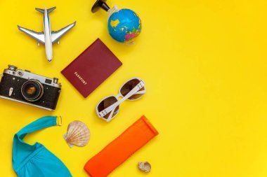 Düz Lay Bikini, çınar, bağbozumu kamera, dünya, Güneş kremi, pasaport, güneş gözlüğü ve kabuk üzerinde sarı renkli şık modern moda arka plan ile. Tatil seyahat yaz hafta sonu deniz macera seyahat kavramı