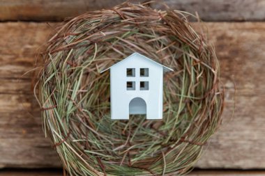Minyatür beyaz oyuncak model house rustik eski vintage ahşap arka plan üzerinde yuvada aittir. Eko köyü çevre gayrimenkul ipotek Emlak sigorta rüya ev ekoloji yatırım kavramı