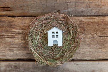 Minyatür beyaz oyuncak model house rustik eski vintage ahşap arka plan üzerinde yuvada aittir. Eko köyü çevre gayrimenkul ipotek Emlak sigorta rüya ev ekoloji yatırım kavramı