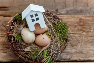 Minyatür beyaz oyuncak model house rustik eski vintage ahşap arka plan üzerinde yumurta yuvada aittir. Eko köyü çevre gayrimenkul ipotek Emlak sigorta rüya ev ekoloji yatırım kavramı