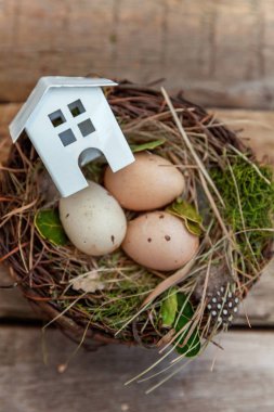 Minyatür beyaz oyuncak model house rustik eski vintage ahşap arka plan üzerinde yumurta yuvada aittir. Eko köyü çevre gayrimenkul ipotek Emlak sigorta rüya ev ekoloji yatırım kavramı