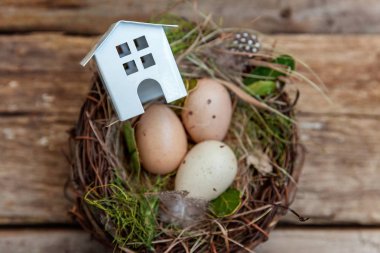 Minyatür beyaz oyuncak model house rustik eski vintage ahşap arka plan üzerinde yumurta yuvada aittir. Eko köyü çevre gayrimenkul ipotek Emlak sigorta rüya ev ekoloji yatırım kavramı
