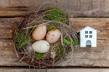 Minyatür beyaz oyuncak model house rustik eski vintage ahşap arka plan üzerinde yumurta yuvada aittir. Eko köyü çevre gayrimenkul ipotek Emlak sigorta rüya ev ekoloji yatırım kavramı