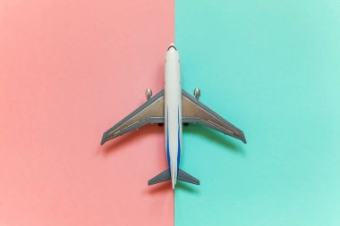 Minyatür oyuncak model uçak mavi ve pembe pastel renkli kağıt trendy geometrik arka plan üzerinde sadece düz yatıyordu tasarım. Uçak tatil yaz hafta sonu deniz macera seyahat kavramı ile seyahat