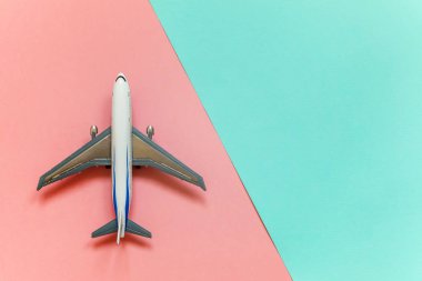Minyatür oyuncak model uçak mavi ve pembe pastel renkli kağıt trendy geometrik arka plan üzerinde sadece düz yatıyordu tasarım. Uçak tatil yaz hafta sonu deniz macera seyahat kavramı ile seyahat