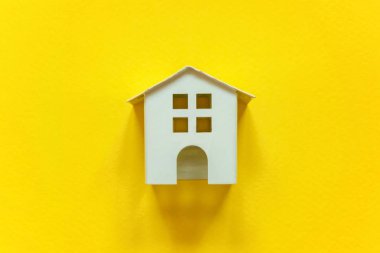 Minyatür beyaz oyuncak ev sarı renkli kağıt trendy arka plan üzerinde sadece düz yatıyordu tasarım. Mortgage Emlak sigorta rüya ev concept