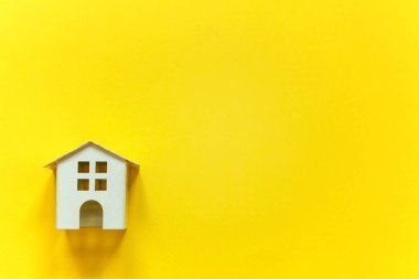 Minyatür beyaz oyuncak ev sarı renkli kağıt trendy arka plan üzerinde sadece düz yatıyordu tasarım. Mortgage Emlak sigorta rüya ev concept
