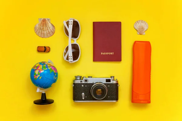 Flat Lay with sunscreen, plane, vintage camera, passport, globe, sunglasses and shell on yellow colourful trendy modern fashion background. Vacation travel summer weekend sea adventure trip concept