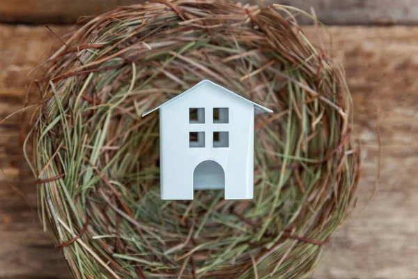 Minyatür beyaz oyuncak model house rustik eski vintage ahşap arka plan üzerinde yuvada aittir. Eko köyü çevre gayrimenkul ipotek Emlak sigorta rüya ev ekoloji yatırım kavramı