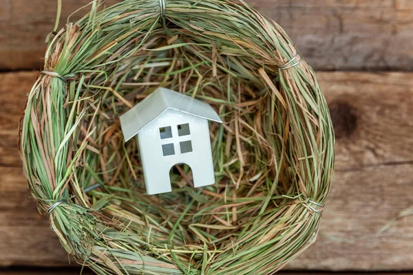 Minyatür beyaz oyuncak model house rustik eski vintage ahşap arka plan üzerinde yuvada aittir. Eko köyü çevre gayrimenkul ipotek Emlak sigorta rüya ev ekoloji yatırım kavramı