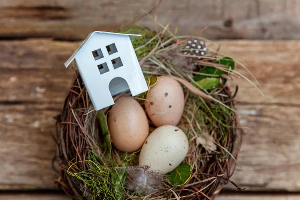 Minyatür beyaz oyuncak model house rustik eski vintage ahşap arka plan üzerinde yumurta yuvada aittir. Eko köyü çevre gayrimenkul ipotek Emlak sigorta rüya ev ekoloji yatırım kavramı