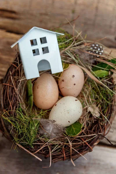 Minyatür beyaz oyuncak model house rustik eski vintage ahşap arka plan üzerinde yumurta yuvada aittir. Eko köyü çevre gayrimenkul ipotek Emlak sigorta rüya ev ekoloji yatırım kavramı