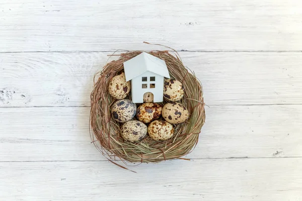Minyatür beyaz oyuncak model house rustik eski vintage ahşap arka plan üzerinde yumurta yuvada aittir. Eko köyü çevre gayrimenkul ipotek Emlak sigorta rüya ev ekoloji yatırım kavramı