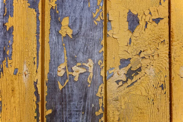 Vintage old background from a wooden shabby plank with peeling yellow paint