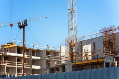 Vinçler ve mavi gökyüzü inşaat sahasında işçiler