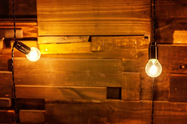Hanging light bulbs over the wooden background, mockup poster. Background wood planks with lamps