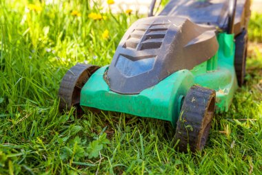 Çim biçme güneşli bir günde bahçede yeşil çim kesme makinesi. Bahçe ülke yaşam tarzı arka plan. Güzel görünüm taze yeşil çim çim güneş ışığı altında bahar ya da yaz sezonu Bahçe Peyzaj