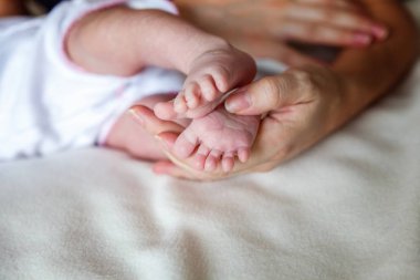 Bebek ayakları annenin ellerinde. Minik Yeni Doğmuş Bebek 'in ayakları dişi şekilli ellerde, yakın plan. Annesi ve çocuğu. Mutlu Aile kavramı. Anneliğin güzel kavramsal görüntüsü