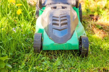 Çim biçme güneşli bir günde bahçede yeşil çim kesme makinesi. Bahçe ülke yaşam tarzı arka plan. Güzel görünüm taze yeşil çim çim güneş ışığı altında bahar ya da yaz sezonu Bahçe Peyzaj