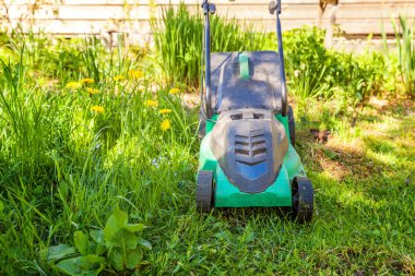 Çim biçme güneşli bir günde bahçede yeşil çim kesme makinesi. Bahçe ülke yaşam tarzı arka plan. Güzel görünüm taze yeşil çim çim güneş ışığı altında bahar ya da yaz sezonu Bahçe Peyzaj