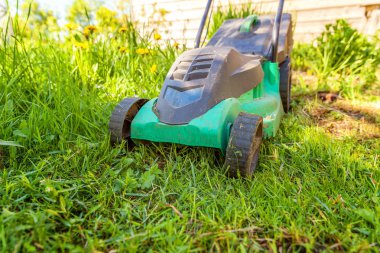 Çim biçme güneşli bir günde bahçede yeşil çim kesme makinesi. Bahçe ülke yaşam tarzı arka plan. Güzel görünüm taze yeşil çim çim güneş ışığı altında bahar ya da yaz sezonu Bahçe Peyzaj