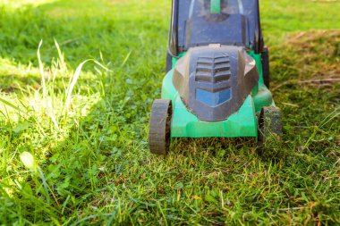 Çim biçme güneşli bir günde bahçede yeşil çim kesme makinesi. Bahçe ülke yaşam tarzı arka plan. Güzel görünüm taze yeşil çim çim güneş ışığı altında bahar ya da yaz sezonu Bahçe Peyzaj