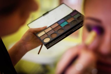 Kozmetik güzellik yordamlar ve baştan yaratma kavramı. Kadın profesyonel makyaj paleti tutar. Makyaj uygulamak