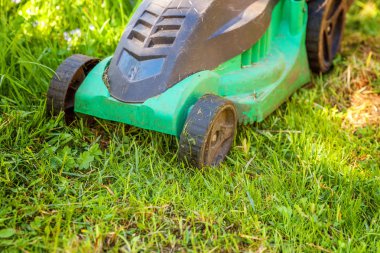 Çim biçme güneşli bir günde bahçede yeşil çim kesme makinesi. Bahçe ülke yaşam tarzı arka plan. Güzel görünüm taze yeşil çim çim güneş ışığı altında bahar ya da yaz sezonu Bahçe Peyzaj
