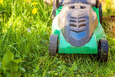 Çim biçme güneşli bir günde bahçede yeşil çim kesme makinesi. Bahçe ülke yaşam tarzı arka plan. Güzel görünüm taze yeşil çim çim güneş ışığı altında bahar ya da yaz sezonu Bahçe Peyzaj