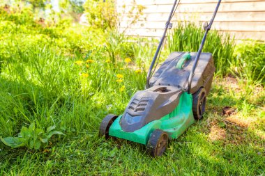 Çim biçme güneşli bir günde bahçede yeşil çim kesme makinesi. Bahçe ülke yaşam tarzı arka plan. Güzel görünüm taze yeşil çim çim güneş ışığı altında bahar ya da yaz sezonu Bahçe Peyzaj
