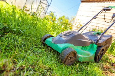 Çim biçme güneşli bir günde bahçede yeşil çim kesme makinesi. Bahçe ülke yaşam tarzı arka plan. Güzel görünüm taze yeşil çim çim güneş ışığı altında bahar ya da yaz sezonu Bahçe Peyzaj