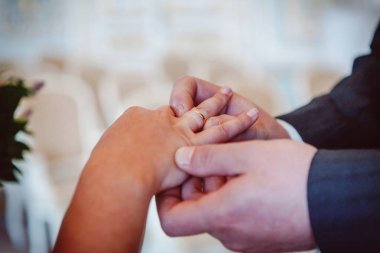 Damadın eli gelinin parmağına alyans takıyor.