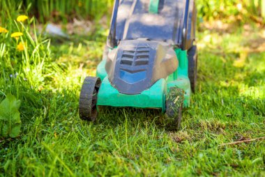 Çim biçme güneşli bir günde bahçede yeşil çim kesme makinesi. Bahçe ülke yaşam tarzı arka plan. Güzel görünüm taze yeşil çim çim güneş ışığı altında bahar ya da yaz sezonu Bahçe Peyzaj