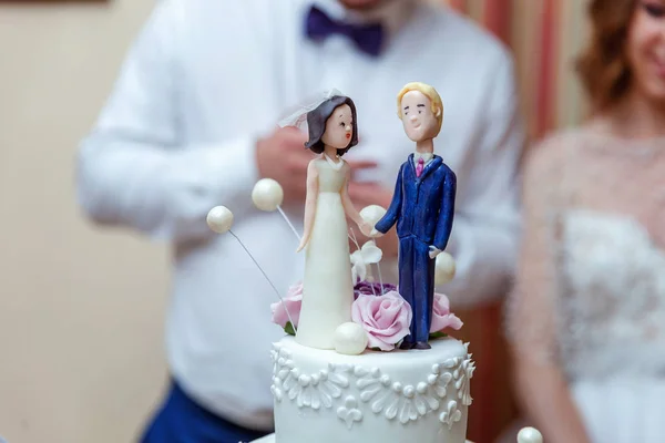 A wedding cake topper on top of the newlyweds dessert