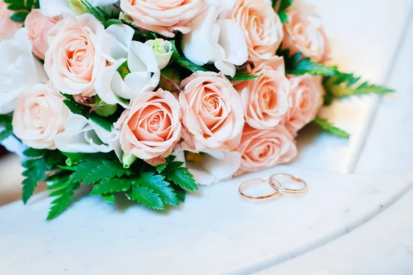 Belos Anéis Casamento Estão Uma Mesa Contra Fundo Buquê Flores — Fotografia de Stock
