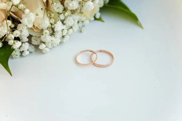 Krásné Snubní Prsteny Leží Stole Pozadí Kytici Květin — Stock fotografie