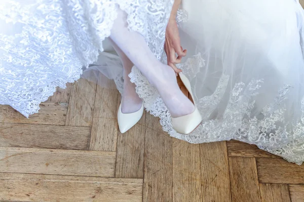 the bride wears white shoes on foot in the wedding day. close-up shoot
