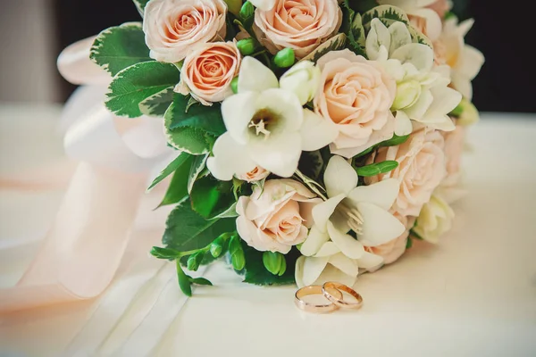 Belos Anéis Casamento Estão Uma Mesa Contra Fundo Buquê Flores — Fotografia de Stock