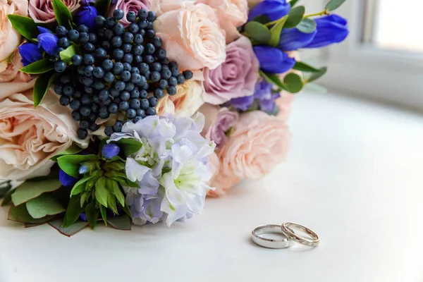 Belos Anéis Casamento Estão Uma Mesa Contra Fundo Buquê Flores — Fotografia de Stock