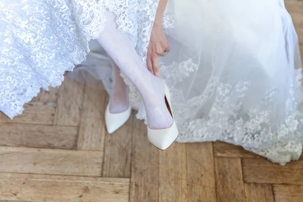 the bride wears white shoes on foot in the wedding day. close-up shoot