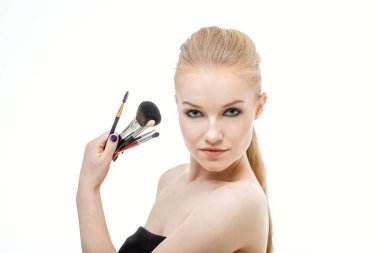 Makyaj fırçaları yanında çekici yüzü ile güzel bir kadın portresi. Yetişkin kız beyaz arka plan üzerinde poz