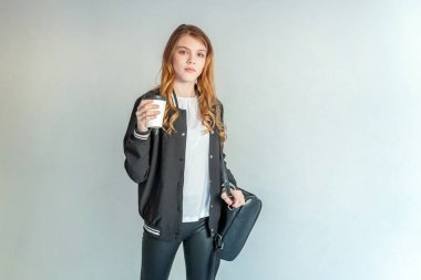 Kağıt bardak tutan ve kahve içme genç Genç kız beyaz duvara, deri ceketli. Sıradan günlük yaşam. Hipster rock tarzı kıyafet giymiş seksi moda şehvetli kadın